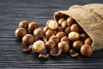 Macadamia are poured out of the bag on a black table, close-up.
