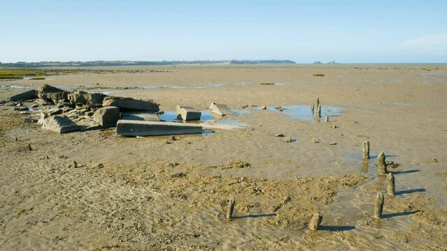 Panoramic view of the coastline of Saint Benoit Des Ondes, Brittany, France, during low tide. In the foreground a rudimentary site for oysters cultivation. Atlantic ocean on the background.