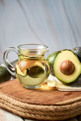 Avocado oil and avocado halved, on a rustic background.