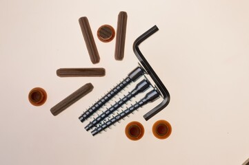 self-tapping screws, hexagons and a screwdriver lie on a light background. close-up