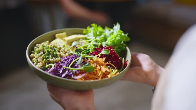 The waiter in a cozy cafe brought a vegetarian dish for a couple of visitors. The staff serves a man and a woman during lunch