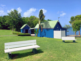White wooden benches and typical blue huts in a garden in the French West Indies. Nature and...