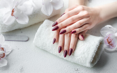 Hands of a young woman with dark red manicure on nails
