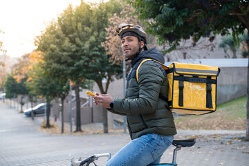 Food delivery concept. Young black man driver with backpack looking smart phone in the city to deliver products for customers who order online purchases. Black male happy with his job.