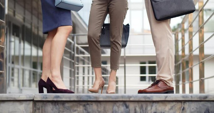 Cropped shot of three business people legs outside office building
