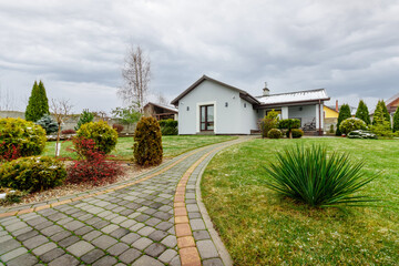 Guest house with green lawn and plants, with a small amount of snow falling