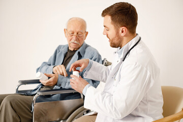 Male doctor and old man on a wheelchair isolated on a white background