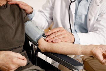 Cropped photo of doctor's hands measuring of man's arterial pressure