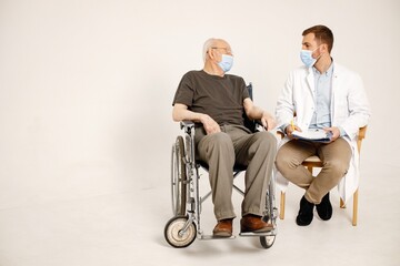 Male doctor and old man on a wheelchair isolated on a white background