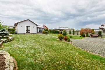 Guest house with green lawn and plants, with a small amount of snow falling