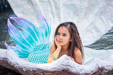 A beautiful girl in a mermaid costume in a large sea shell
