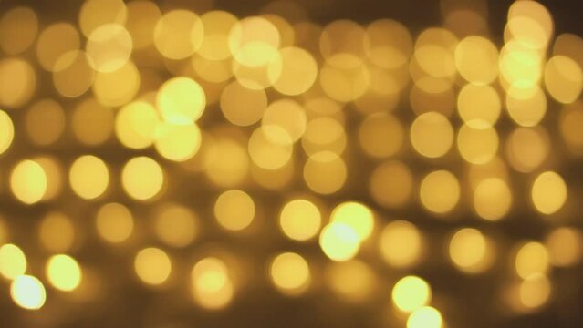 Out of focus holiday background. Light bokeh from Xmas tree. New Year theme, background 4k footage. Christmas lights, shimmering abstract golden warm circles defocused. Blurred fairy lights