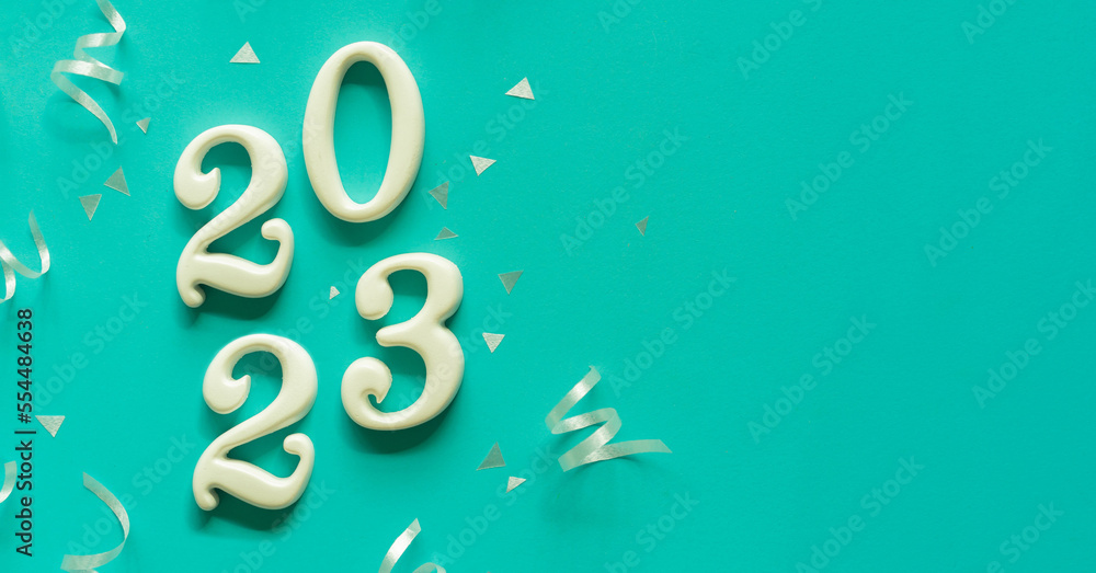 Wall mural close up number 2023 shape wood on blue color background with rolling ribbon and confetti for happy 