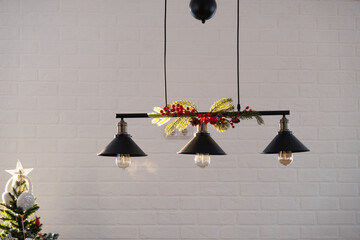The black lampshade in the industrial loft style is decorated with spruce branches for Christmas...