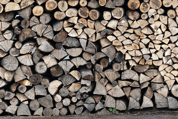 Dry firewood stacked in a pile, chopped wood for winter heating fuel of the fireplace. Natural wood background.