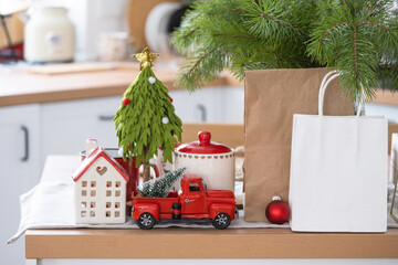 Paper packages mock up are on kitchen served table decorated for Christmas. Shopping and gifts,...