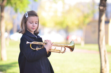 A girl with a trumpet plays outside