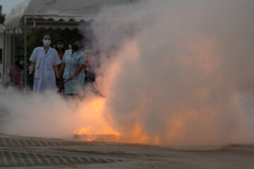 Showing how to use a fire extinguisher on a training fire for employees industry.Fire fighter concept.