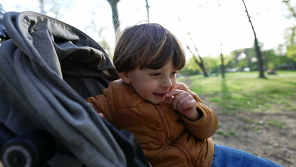 2 year old child sitting in stroller outside at park during autumn season