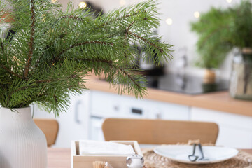 Festive Christmas decor in white kitchen, festive breakfast, white scandi interior. The figure of a cozy house ion the set table. New Year, mood, cozy home. Copy space