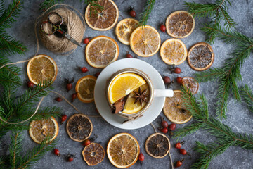 A cup of hot tea with oranges and spices and dried oranges, which are used to make a New Year's garland, 2023 festive background.