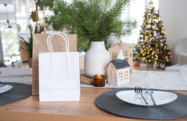 Paper packages mock up are on kitchen served table decorated for Christmas. Shopping and gifts, present and ready meals are delivered and prepared for the new year