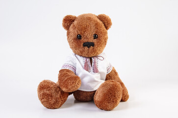Soft toy. Teddy bear in an embroidered shirt on a white background.