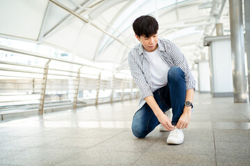 Asian man sit on the ground and tie shoelace.