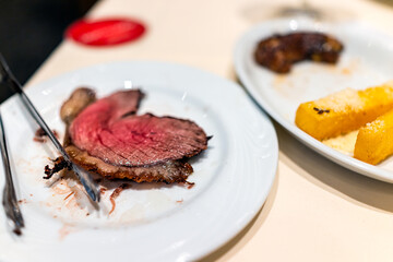 Brazilian steakhouse restaurant table plate with tongs in churrascaria serving barbecued meats...