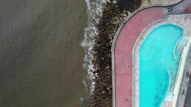 Aerial drone top down view of large swimming pool next to boardwalk in Oeiras, Lisbon Region, Portugal