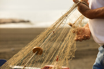fishing net in the hands of a fisherman, preparing gear to go out to sea, in the background the...