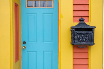 The exterior wall of colorful orange and yellow wooden clapboard siding building with a bright blue...