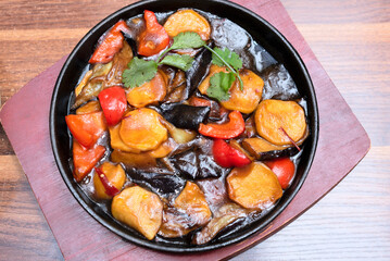 Delicious asian food in cast-iron pan on wooden background. Selective focus. Asian food concept