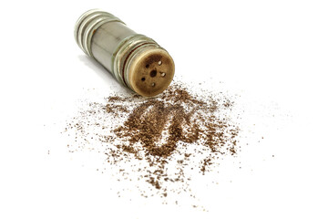 Black allspice ground pepper is scattered from a pepper pot on a white background.