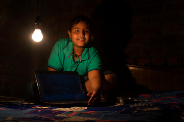 Teenager Indian boy Sitting on Charpai using Laptop at Home