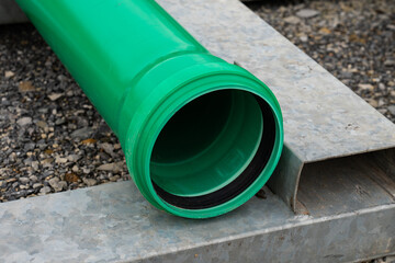 Part of green plastic pipe with a connecting flange at the end. Close-up.