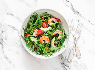 Salad with shrimp, arugula,avocado, cherry tomatoes on a light marble background, top view
