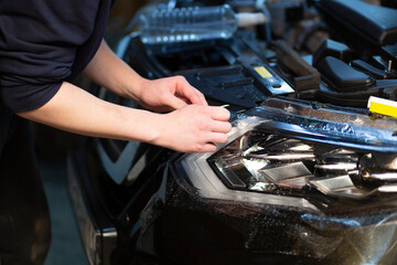 Installation of a protective film on the headlights of the car.Car body protection.