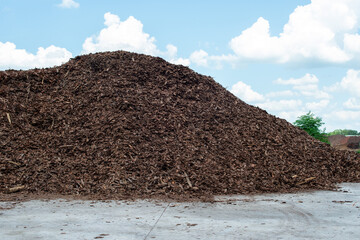 A large industrial stockpile of chipped bark from rough lumber and wooden shavings. The zero waste...