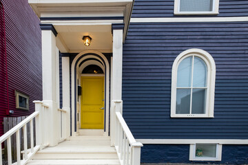A rounded top bright yellow elegant style door in a dark blue colored wooden house. The residence...