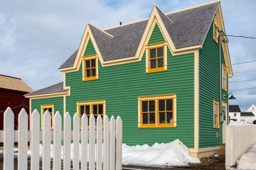 The exterior of a green cape cod clapboard horizontal wooden board style siding wall with two...