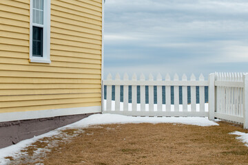 A yellow country style wooden building with a white picket fence attached and enclosing the...