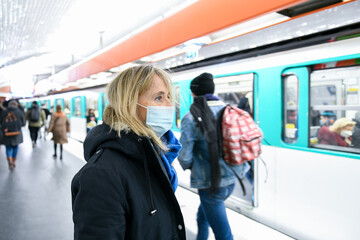 A person (woman) wearing a surgical blue mask on public transport due to the Covid-19 (coronavirus)...
