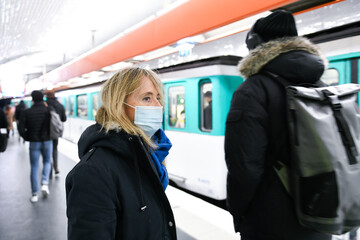 A person (woman) wearing a surgical blue mask on public transport due to the Covid-19 (coronavirus) pandemic in the parisian subway.