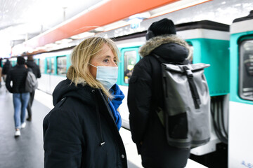 A person (woman) wearing a surgical blue mask on public transport due to the Covid-19 (coronavirus) pandemic in the parisian subway.