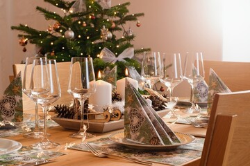Cozy home Christmas interior, festive table arrangement and Christmas tree on the background.