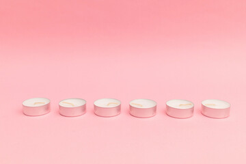 Small candles with wax on a pink background