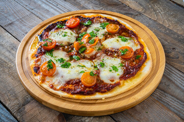 Circle with mozzarella, salami and cherry tomatoes on wooden table
