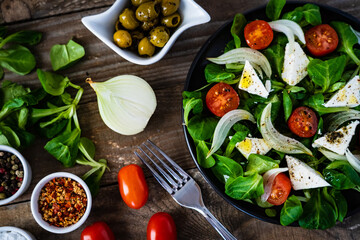 Fresh vegetable salad with feta cheese on wooden table
