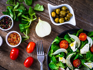 Fresh vegetable salad with feta cheese on wooden table
